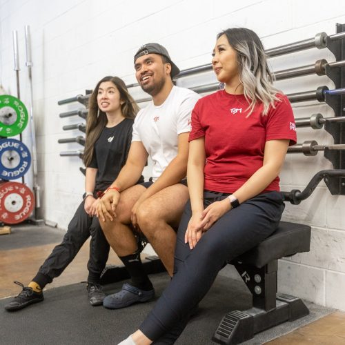 Alicia, Nick and Silvia sitting down on a bench wearing TEM competition shirts